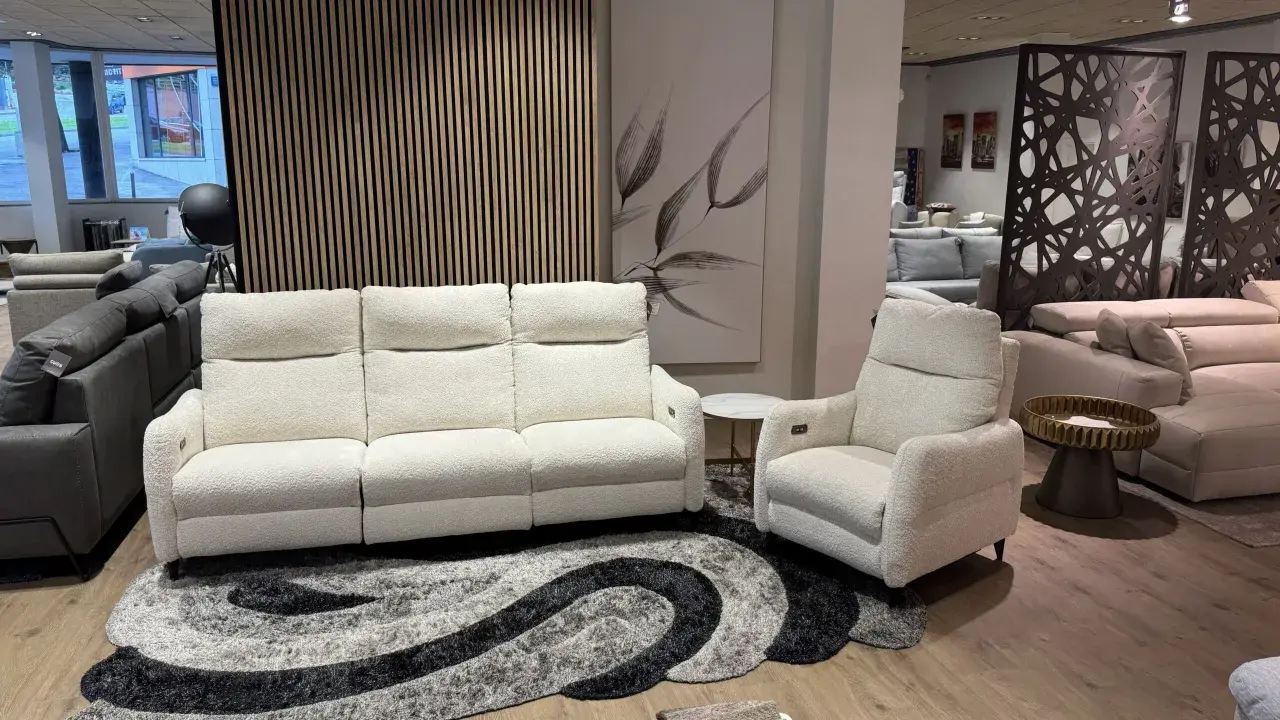 Sofá blanco de tres plazas y butaca a juego, perfectos para combinar sofá y butaca en tu salón. Alfombra moderna y cuadro decorativo.