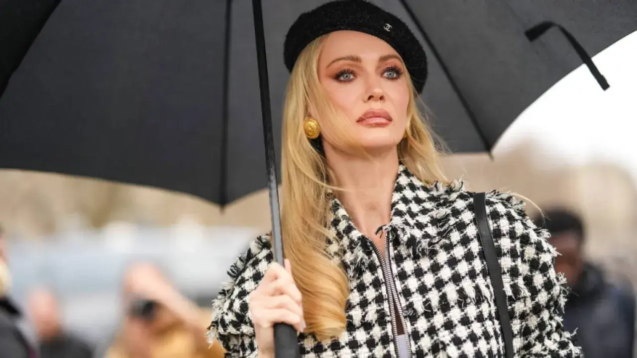 Mujer con boina negra y chaqueta a cuadros, sosteniendo un paraguas. Su maquillaje es un perfecto ejemplo de soft glam.