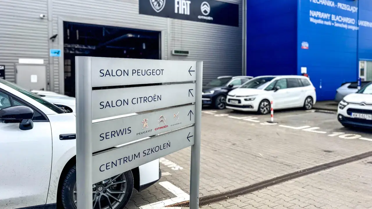 Znak kierunkowskazów w ASO wskazuje salon Peugeot, salon Citroën, serwis i centrum szkoleń.