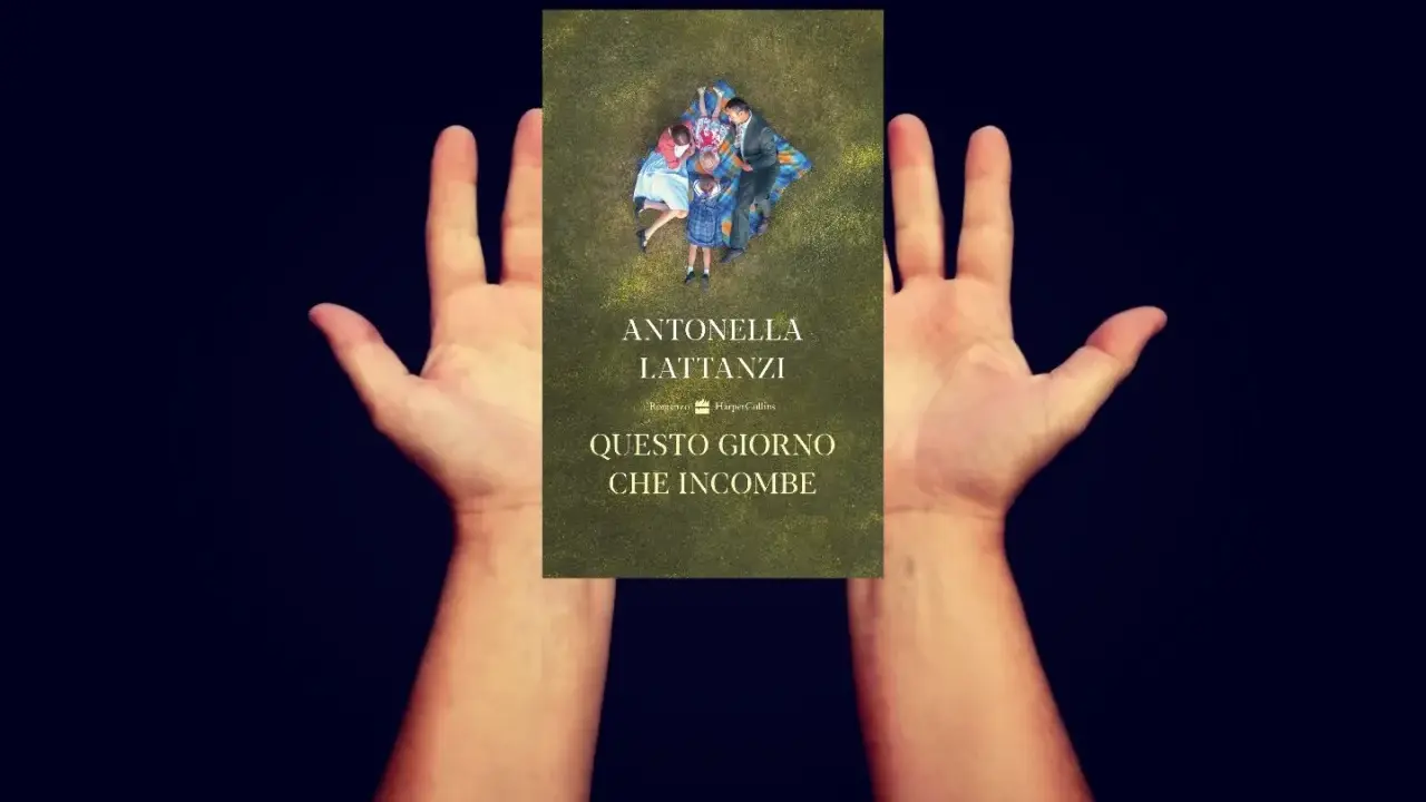 Mani aperte sorreggono la copertina del libro "Questo giorno che incombe", con una famiglia distesa sull'erba.