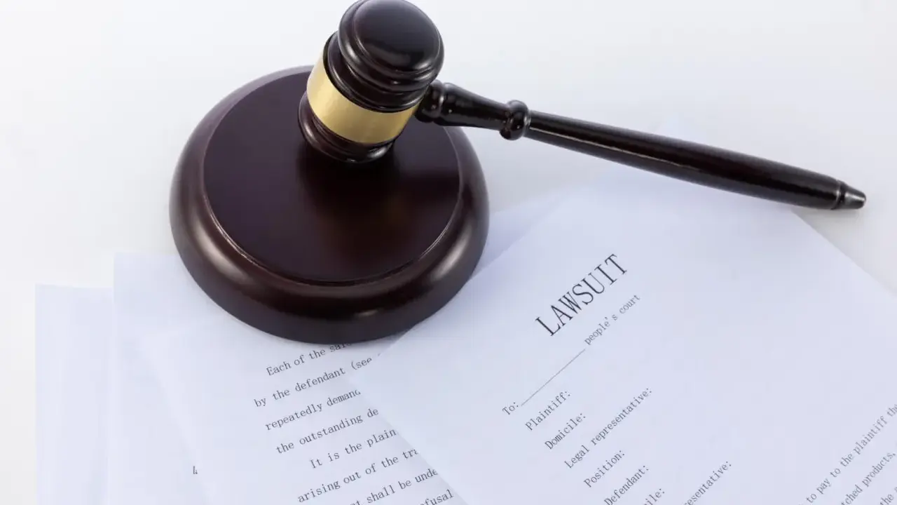 Młotek sędziowski na dokumentach sądowych, w tym na formularzu "LAWSUIT". Może posłużyć jako wzór wniosku o alimenty bez rozwodu.