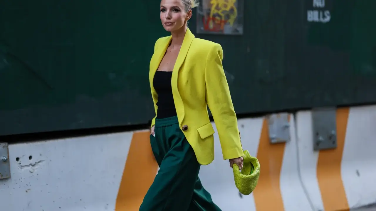 Kobieta w żółtej marynarce i zielonych spodniach, z limonkową torebką. Jej stylizacja to prawdziwe koło kolorów ubrania, łączące energię i elegancję.