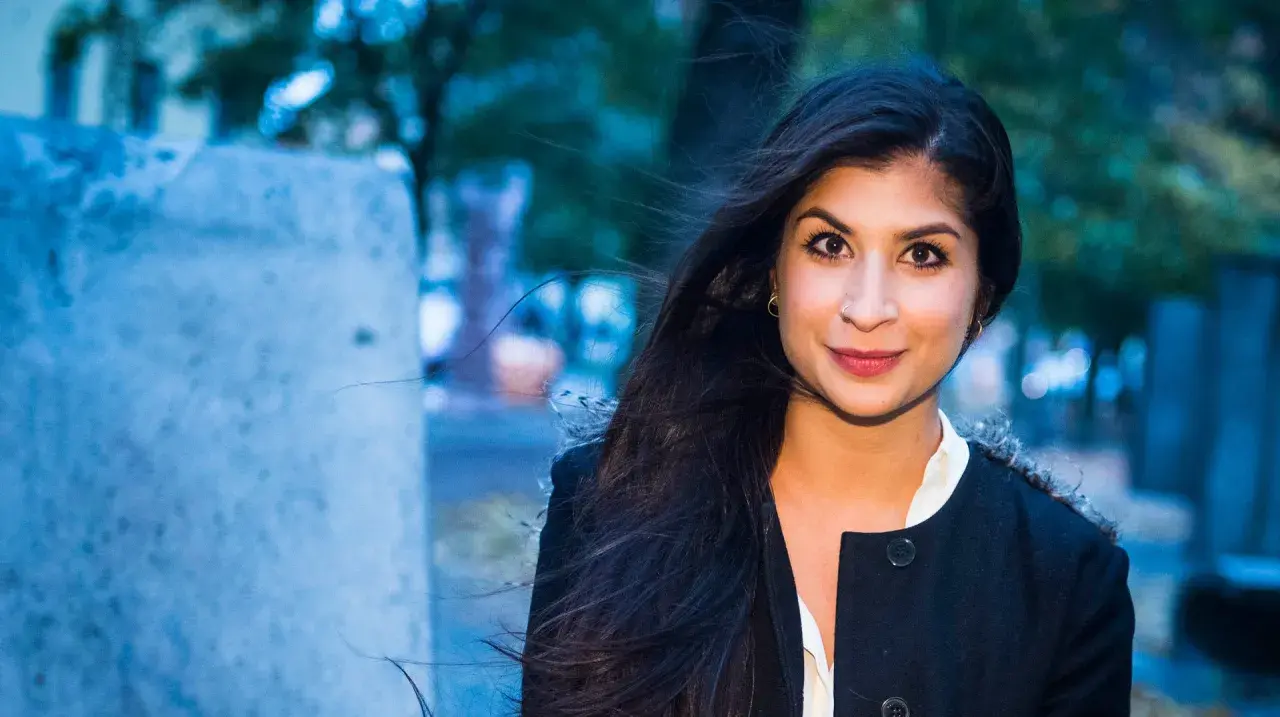 Soraya Hashim ler mot kameran, hennes mörka hår blåser i vinden.