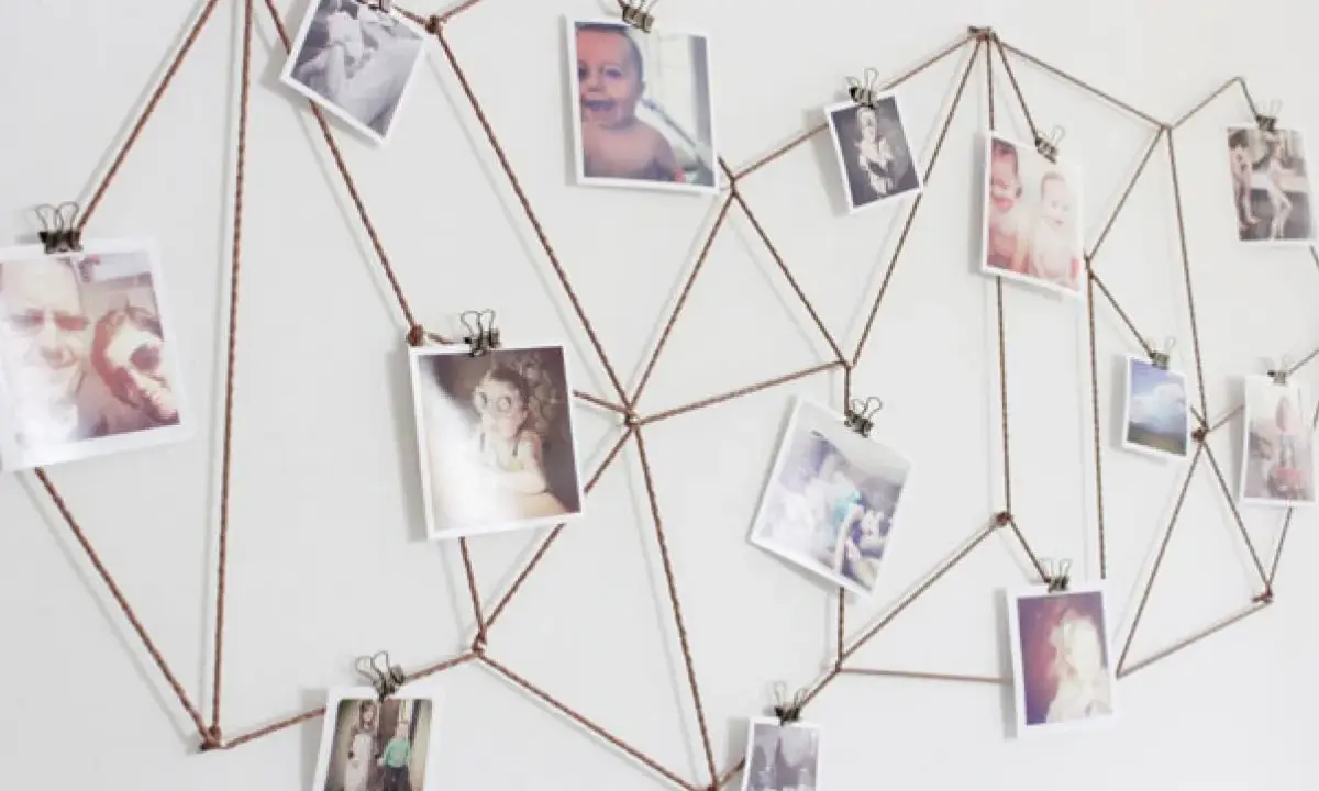Sznurek tworzy geometryczny wzór na ścianie, na którym wiszą zdjęcia. Różnorodne tematy fotografii, od dzieci po krajobrazy, tworzą osobistą galerię.