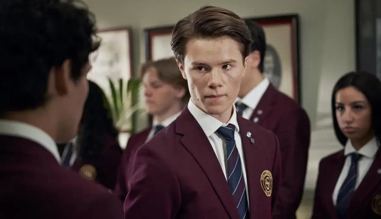 Ungdomar i skoluniformer, en av young royals skådespelare tittar intensivt.