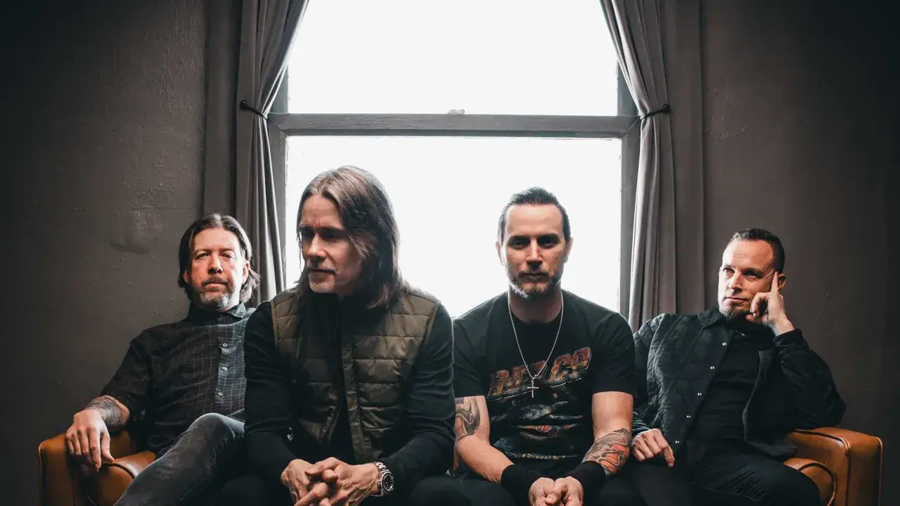 Alter Bridge Sverige: bandmedlemmar sitter på en soffa framför ett fönster.
