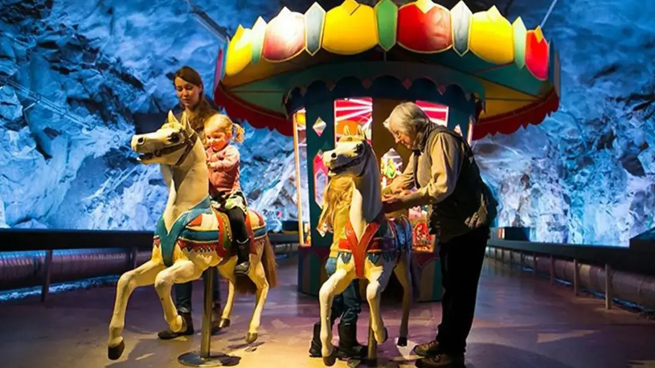 Familj njuter av en karusell i en grottliknande miljö på Stockholm Toy Museum.