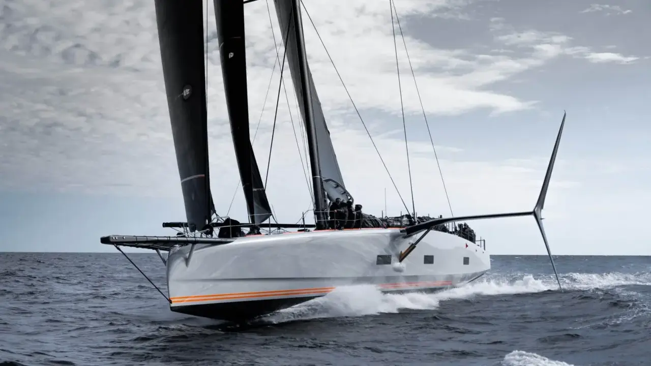 Le voilier Baltic 111 Raven fend les vagues, ses voiles noires gonflées par le vent.