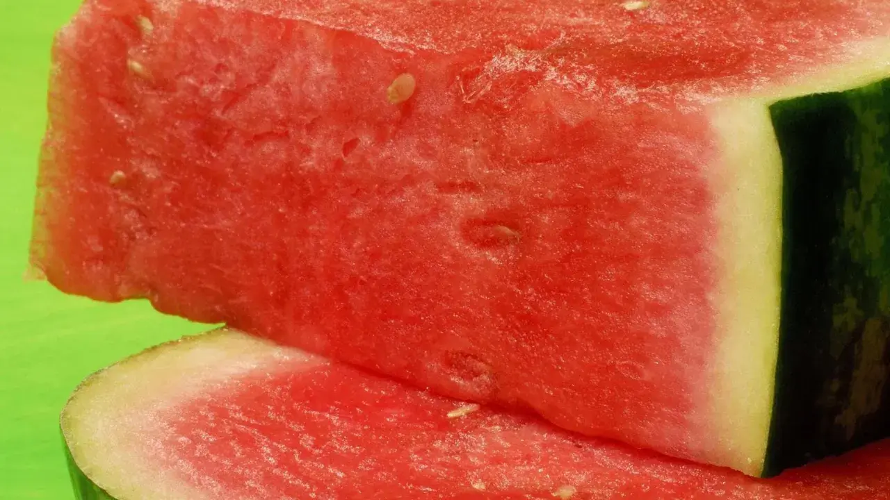 Saftige Wassermelonenstücke auf grünem Hintergrund. Perfekt für eine leichte Erfrischung, da Wassermelone kalorienarm ist.