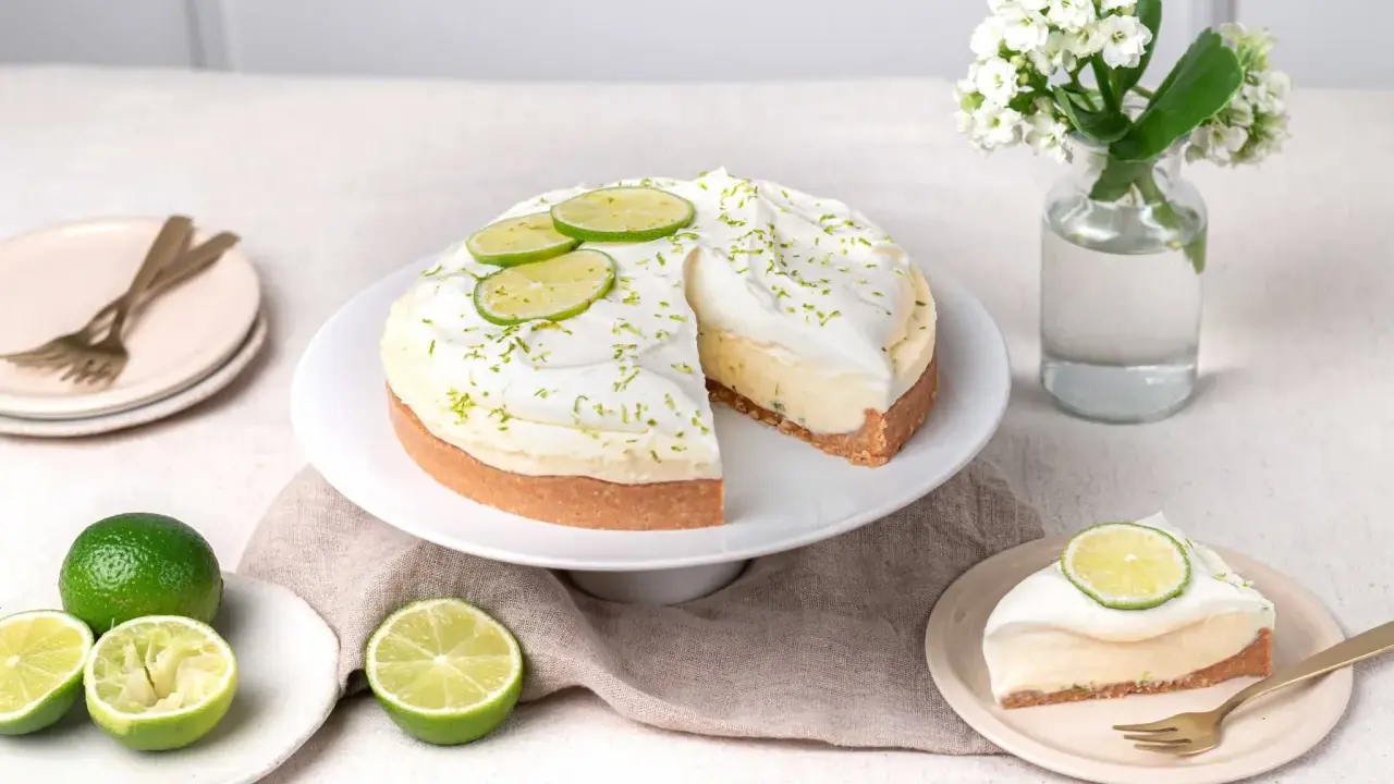 Un cheesecake au citron vert, garni de crème fouettée et de fines tranches de citron vert. Le fromage idéal pour un cheesecake est crémeux et légèrement acidulé.
