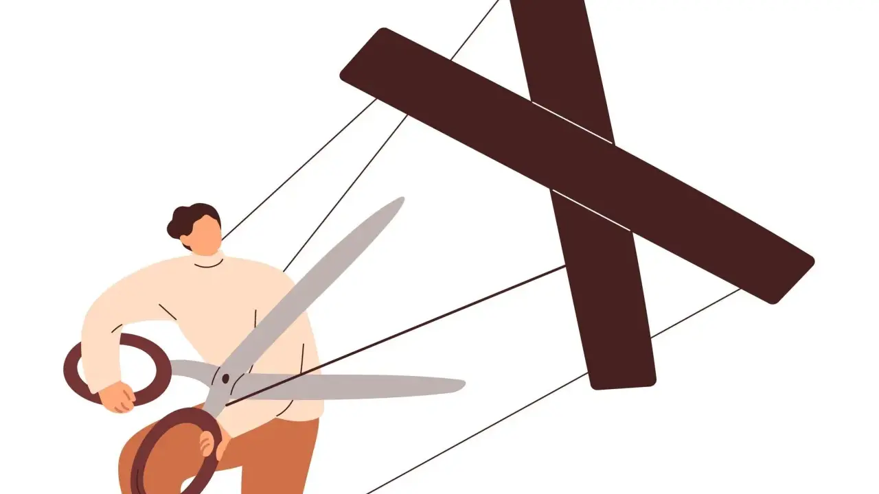 Persona con forbici taglia i fili di un burattino a forma di croce, simboleggiando come destabilizzare un manipolatore.