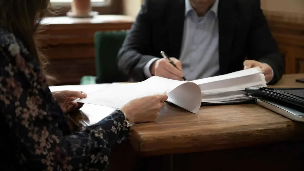 Kobieta i mężczyzna przy biurku przeglądają dokumenty. Sprawa alimentów, gdy nie płaci alimentów kiedy do komornika, wymaga analizy papierów.