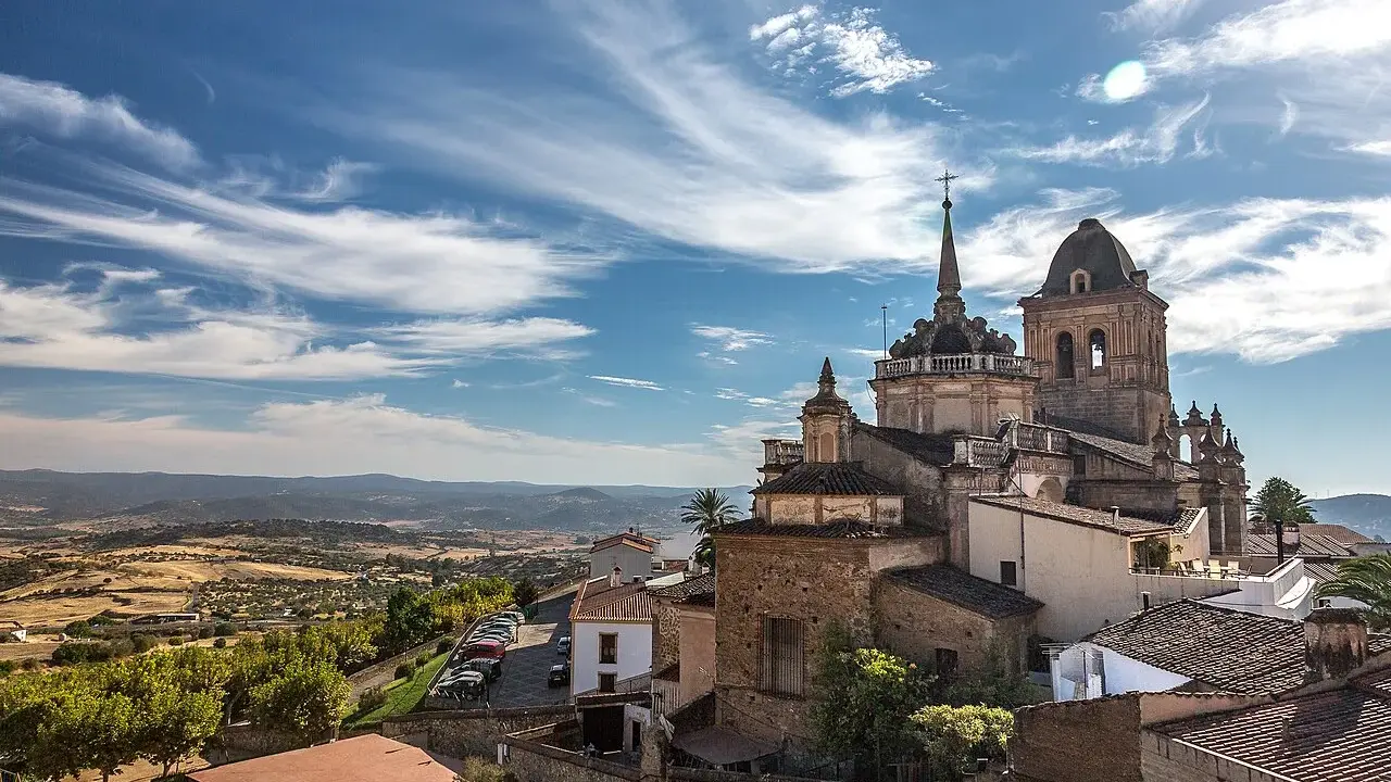 Blick auf die historische Stadt Jerez de los Caballeros mit ihren beeindruckenden Kirchtürmen unter einem dramatischen Himmel.
