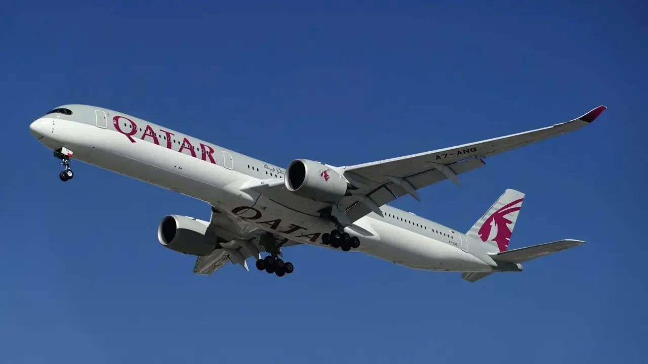 Samolot Qatar Airways z wysuniętym podwoziem, gotowy do lądowania. Idealny do podróży z bagażem podręcznym.