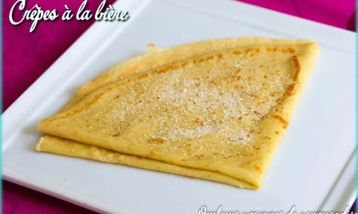 Crêpes à la bière, dorées et saupoudrées de sucre, sur une assiette blanche. Un délice gourmand !
