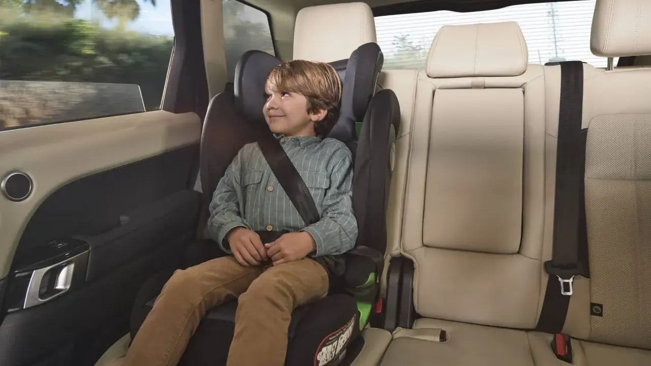 Niño sonriente en una silla de coche grupo 3 edad, viajando seguro y cómodo en el asiento trasero de un vehículo.