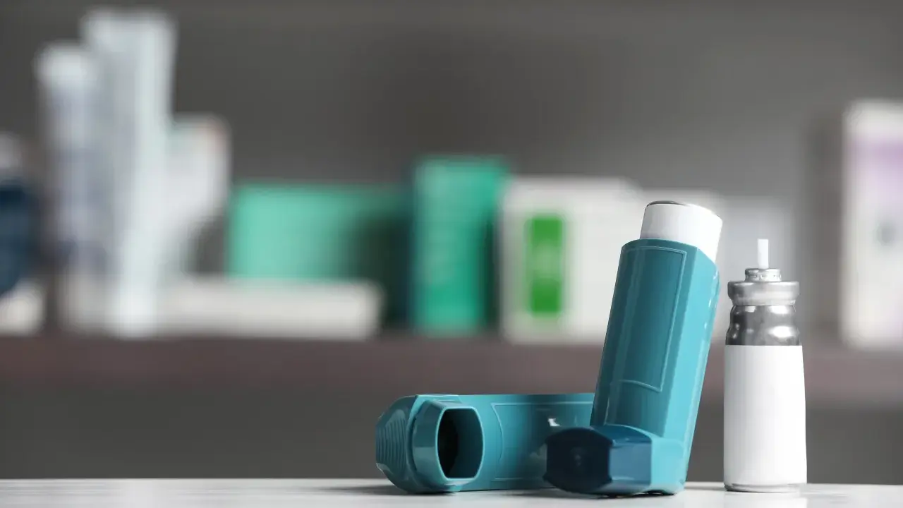 Zwei Inhalatoren, einer davon mit einem silbernen Behälter, liegen auf einer weißen Oberfläche. Sie sind wichtige Hilfsmittel bei der Behandlung von COPD, wo Cortison oft eine Rolle spielt.
