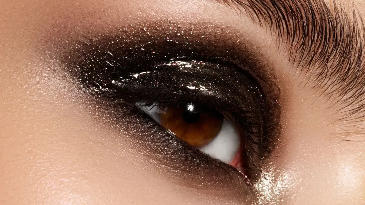 Ojo con un espectacular maquillaje ahumado marrón con brillos intensos y pestañas largas.