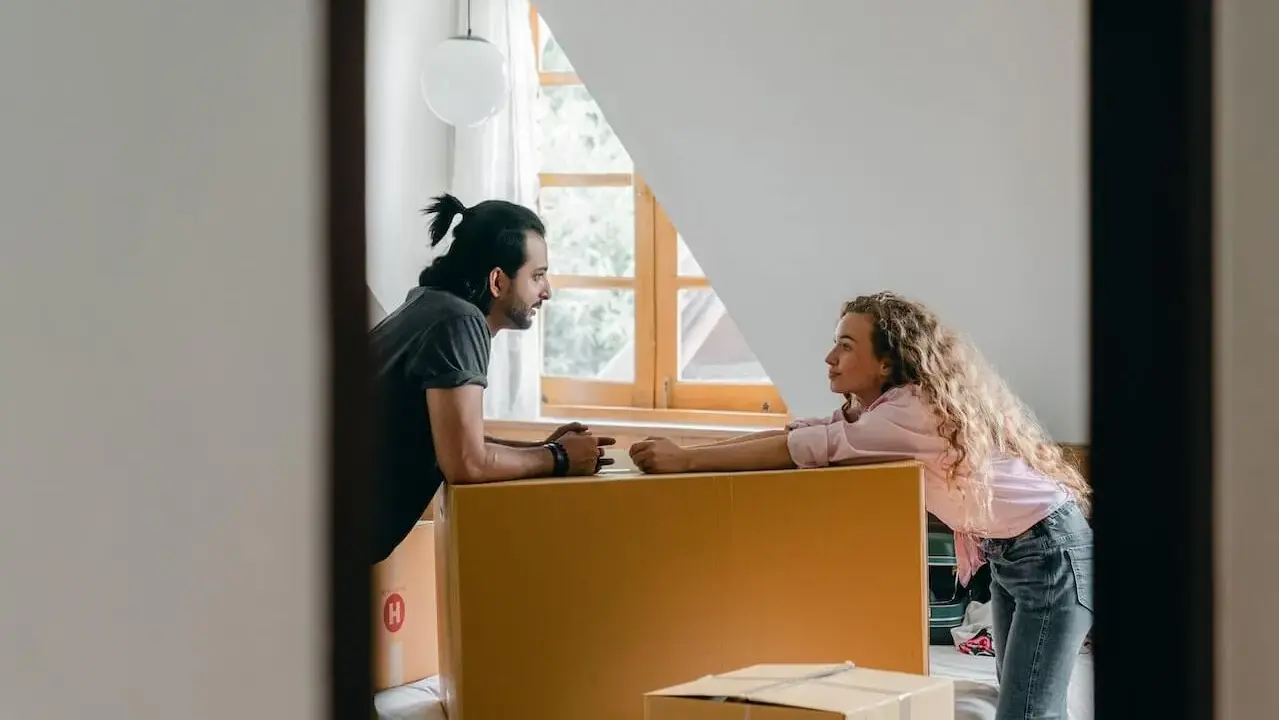 Par diskuterar flytten utomlands, omgivna av flyttkartonger. En checklista för flytten är troligen nära till hands.