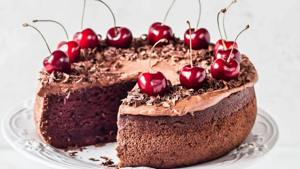 Gâteau chocolat cerise, riche et moelleux, décoré de cerises fraîches et de copeaux de chocolat. Un délice gourmand.