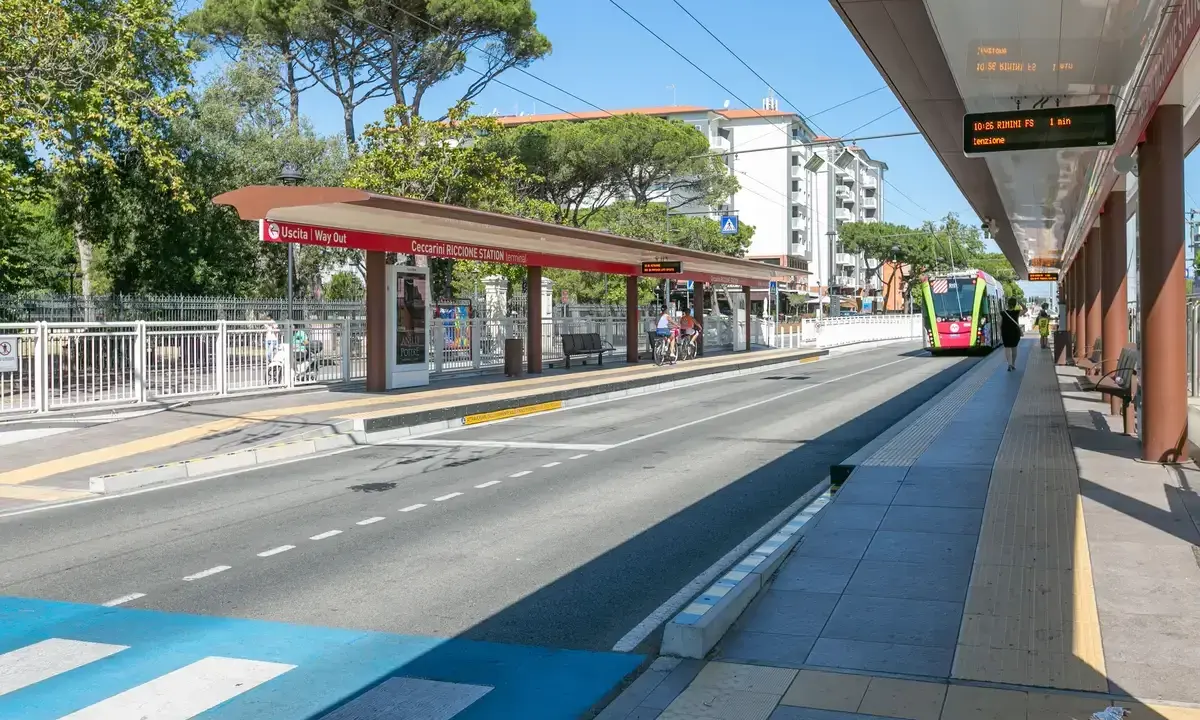 Stazione di Riccione, un tram colorato si avvicina. Perfetto per spostarsi tra Rimini e Riccione in estate.
