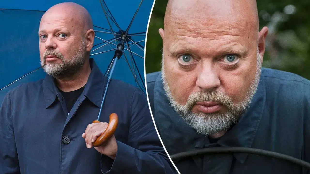 Peter LeMarc, med sitt karakteristiska skalliga huvud och skägg, håller ett blått paraply. En närbild visar hans intensiva blick.