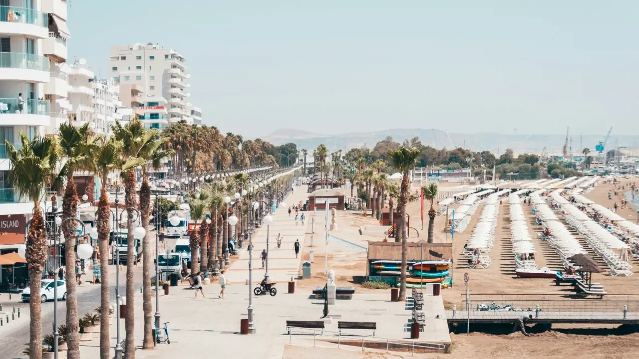 Promenada w Larnace z palmami, białymi budynkami i plażą pełną leżaków. Idealne miejsce, by zobaczyć, co oferuje Larnaka.