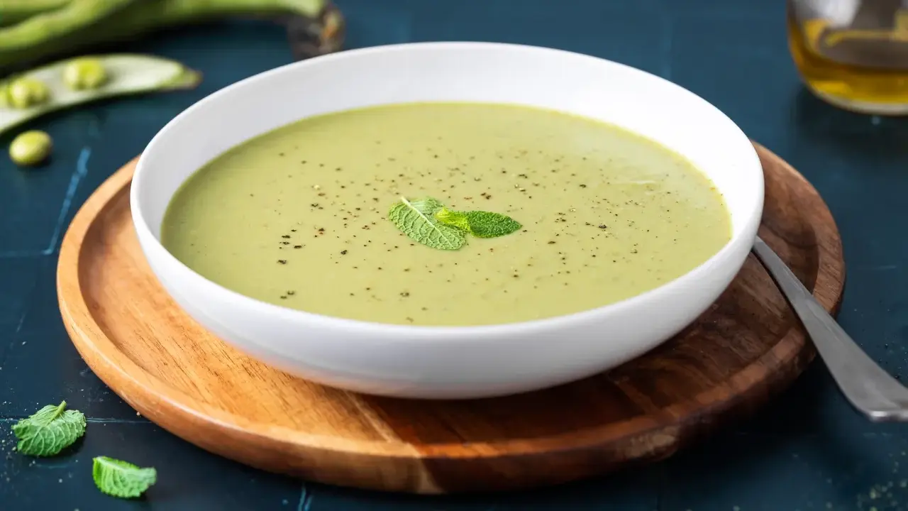 Una ciotola di cremoso purè di fave, guarnito con menta fresca e pepe nero, pronto per essere gustato.