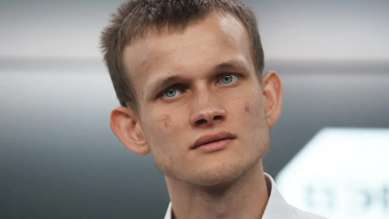 Vitalik Buterin, twórca Ethereum, z niebieskimi oczami i krótkimi włosami, w białej koszuli.