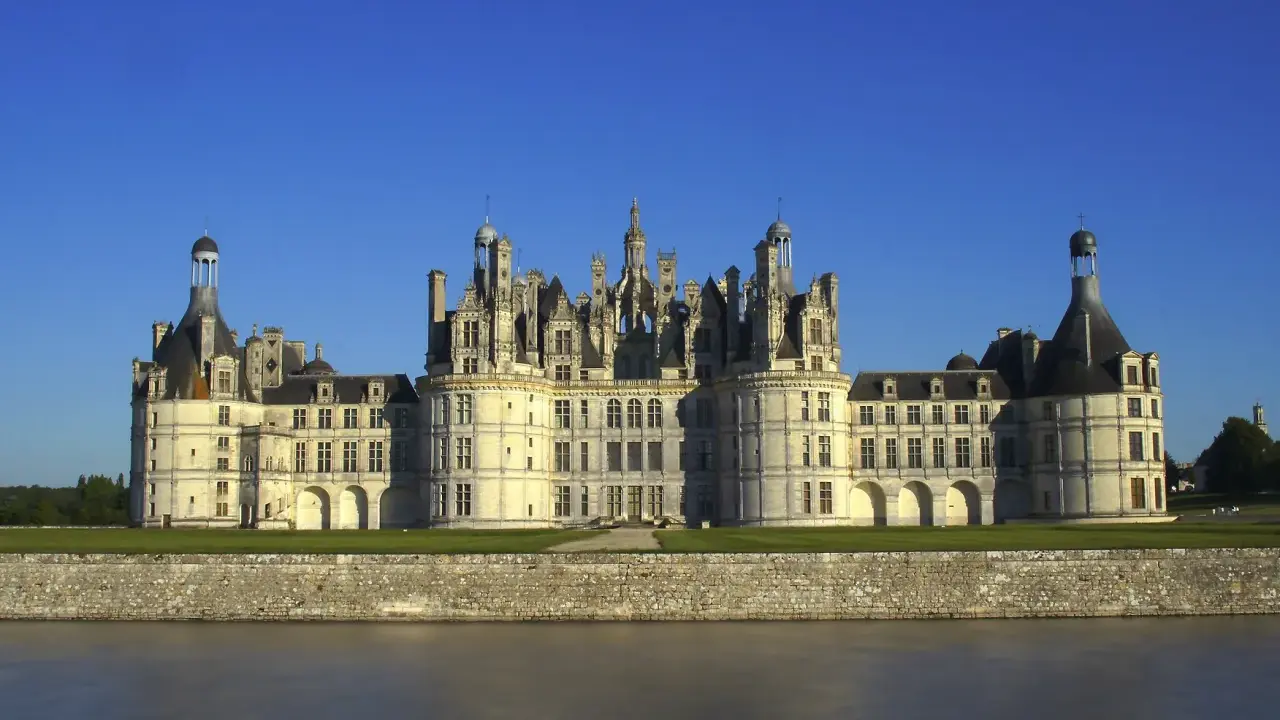 Majestatyczny zamek Chambord, perła Doliny Loary, wznosi się nad spokojną rzeką.