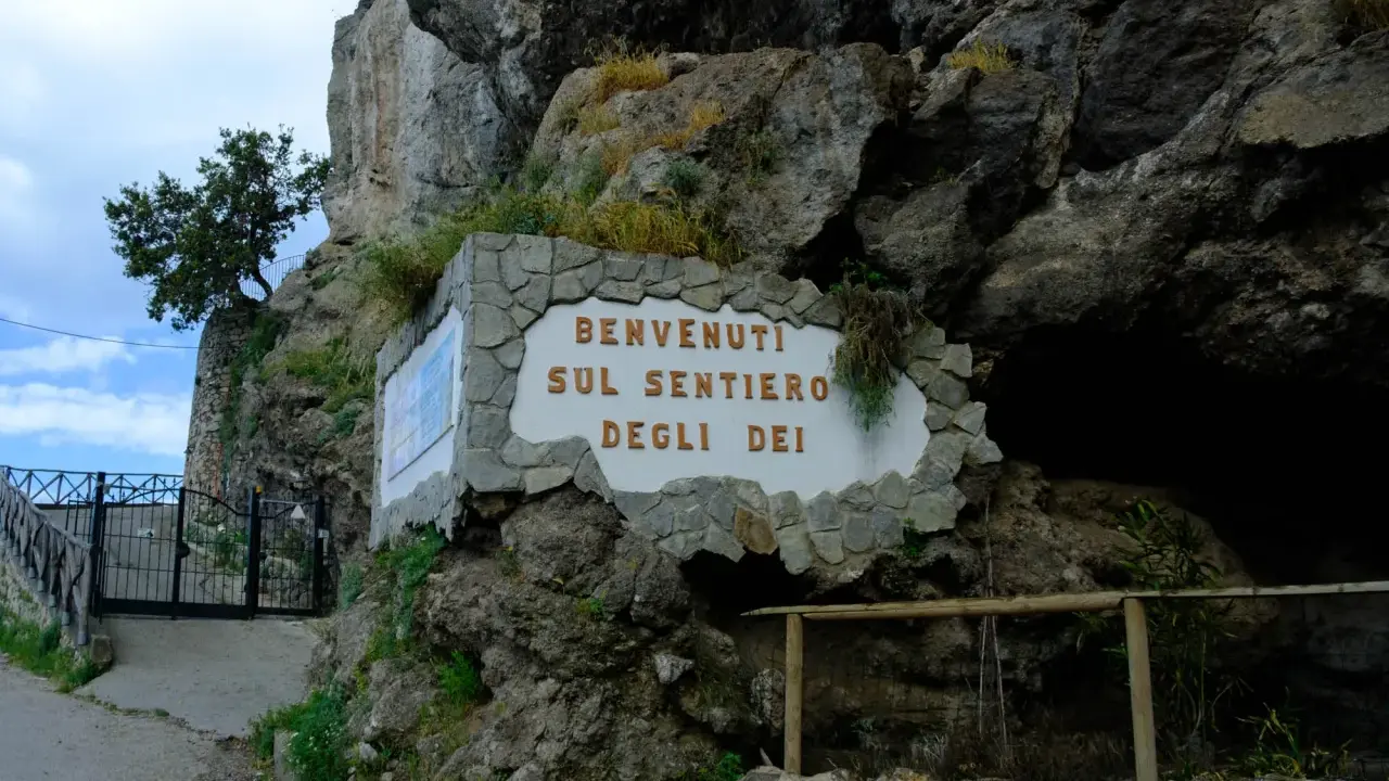 Qui inizia il Sentiero degli Dei, un cartello accoglie i visitatori tra rocce e vegetazione.