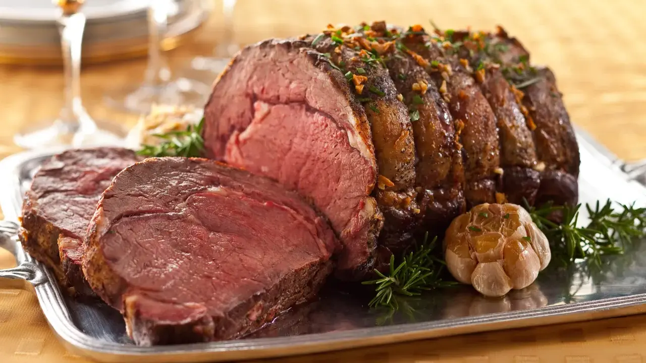Saftiger Rinderbraten (1 kg) mit perfekter Kerntemperatur, garniert mit Rosmarin und Knoblauch auf einem Silbertablett.