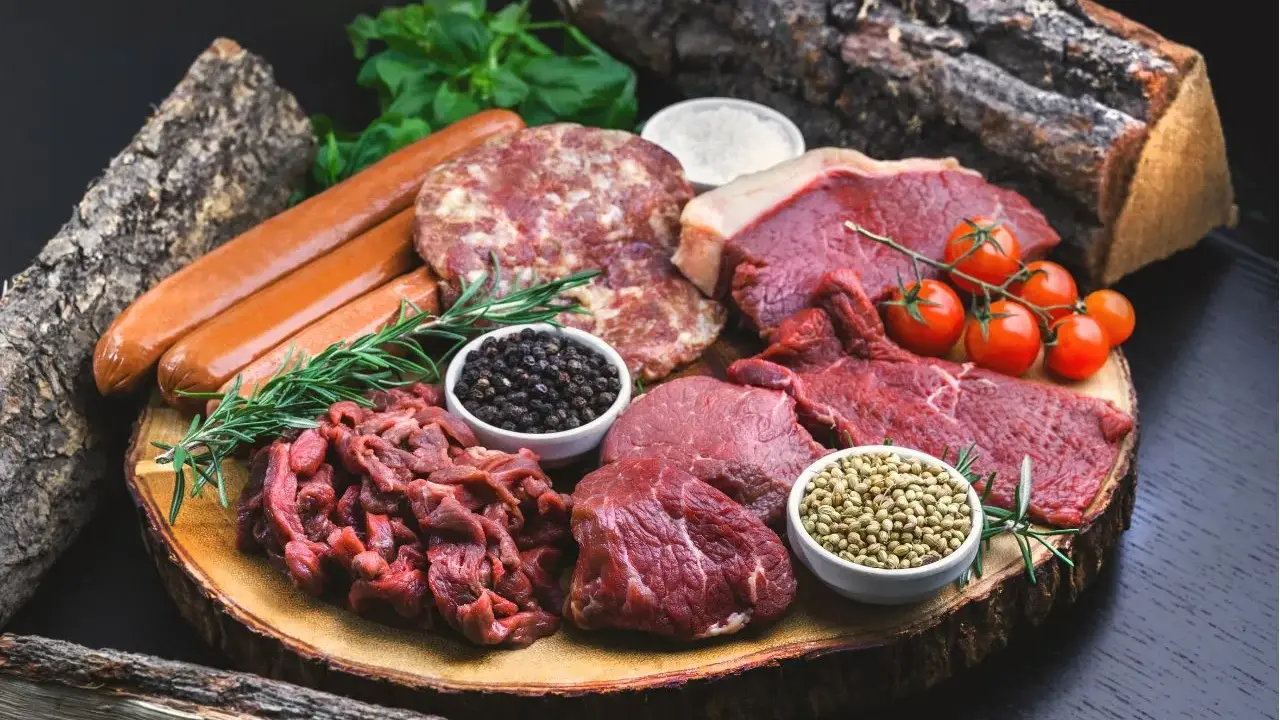 Mięso wołowe, kiełbaski, kotlety i przyprawy na desce. Idealne składniki dla diety carnivore.