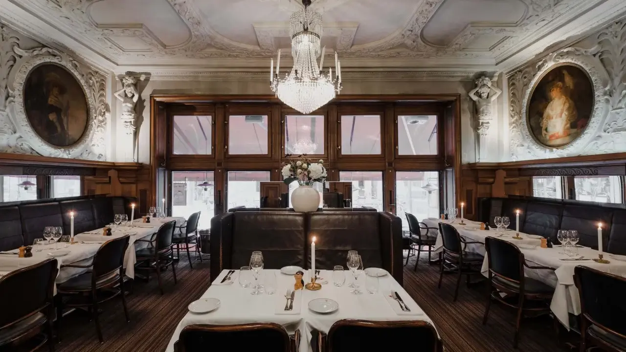 Elegant dukade bord med levande ljus i en av Stockholms gamla restauranger. Kristallkrona och konst pryder taket.
