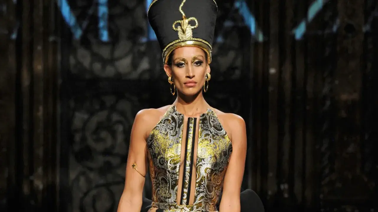 A model wears a striking Nefertiti-inspired headdress and ornate gold and black gown, showcasing the bold vision of Egyptian fashion designers.
