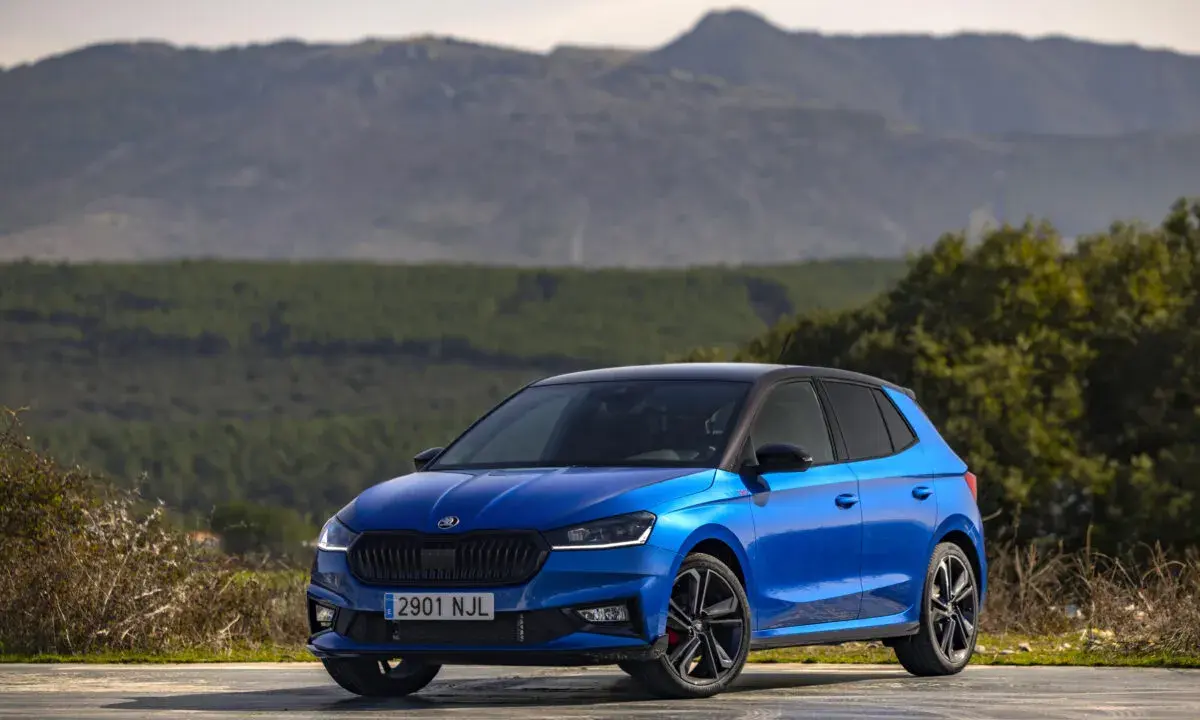 Un Skoda Fabia 130 azul brillante, con techo negro, aparcado en un paisaje montañoso.