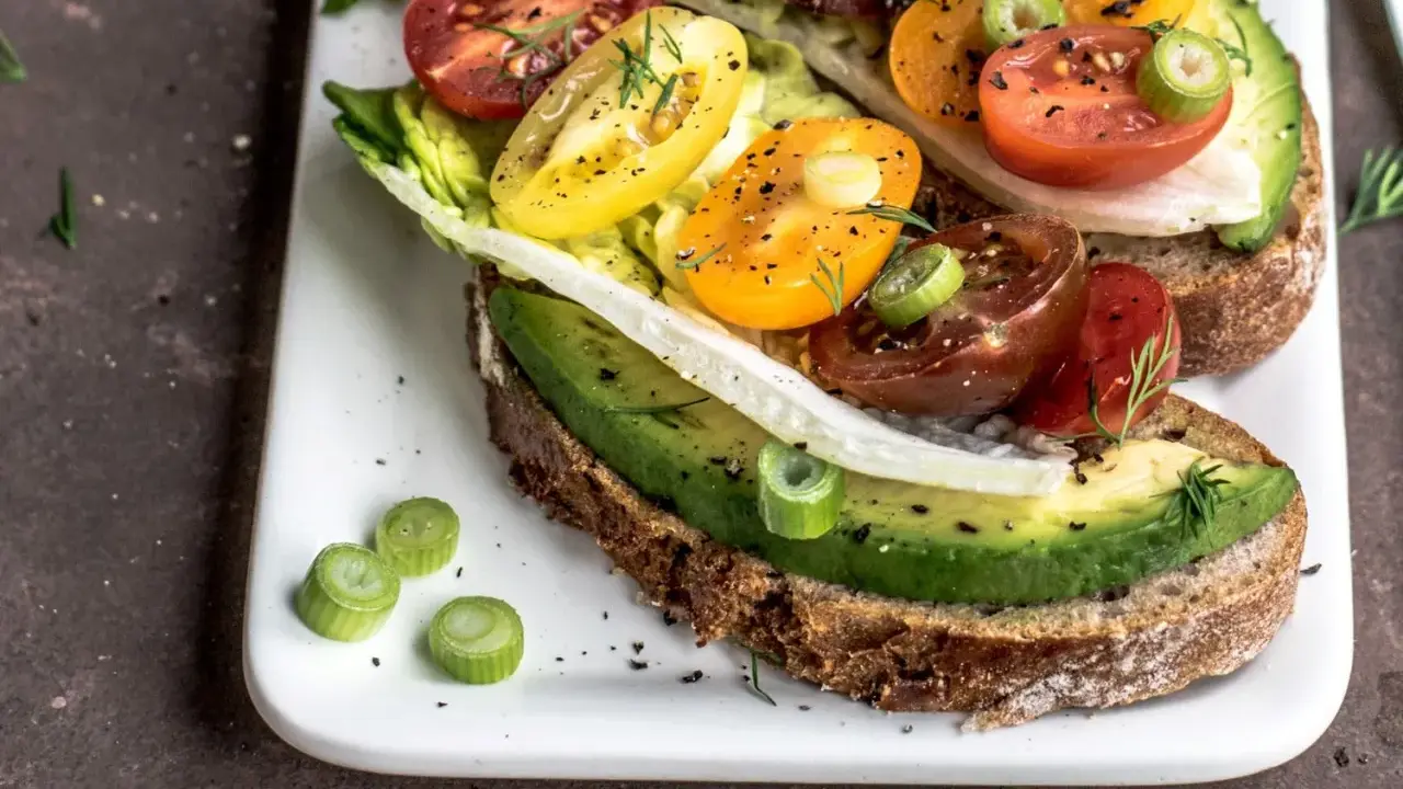 Herzhafte Avocado-Tomaten-Toasts auf Vollkornbrot, garniert mit Frühlingszwiebeln und Dill. Perfekt als kalorienarme Snacks für zwischendurch.
