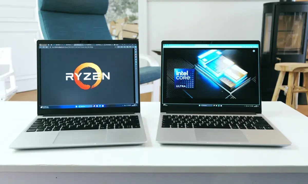 Deux ordinateurs portables côte à côte, l'un affichant le logo Ryzen, l'autre le logo Intel Core Ultra. Un **framework computer** pour chaque processeur.