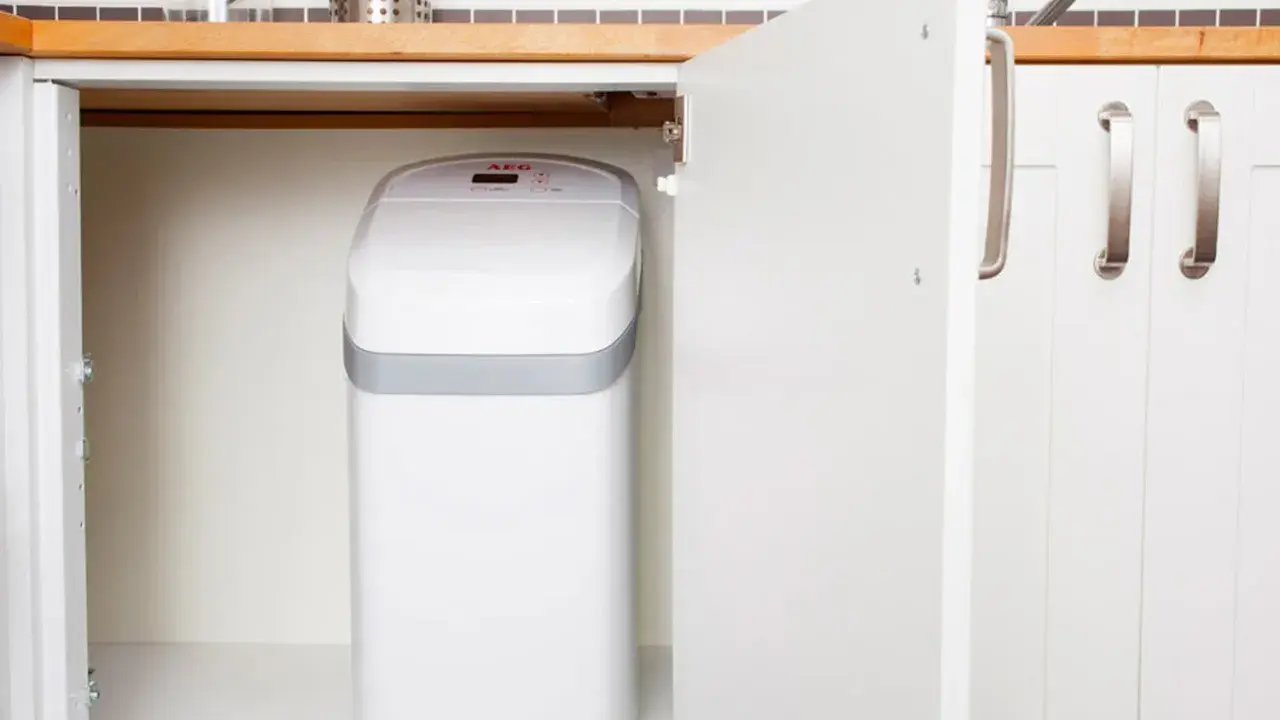 Un adoucisseur d'eau AEG blanc est installé sous un évier de cuisine. C'est une bonne idée de savoir quand installer un adoucisseur d'eau pour une eau plus douce.