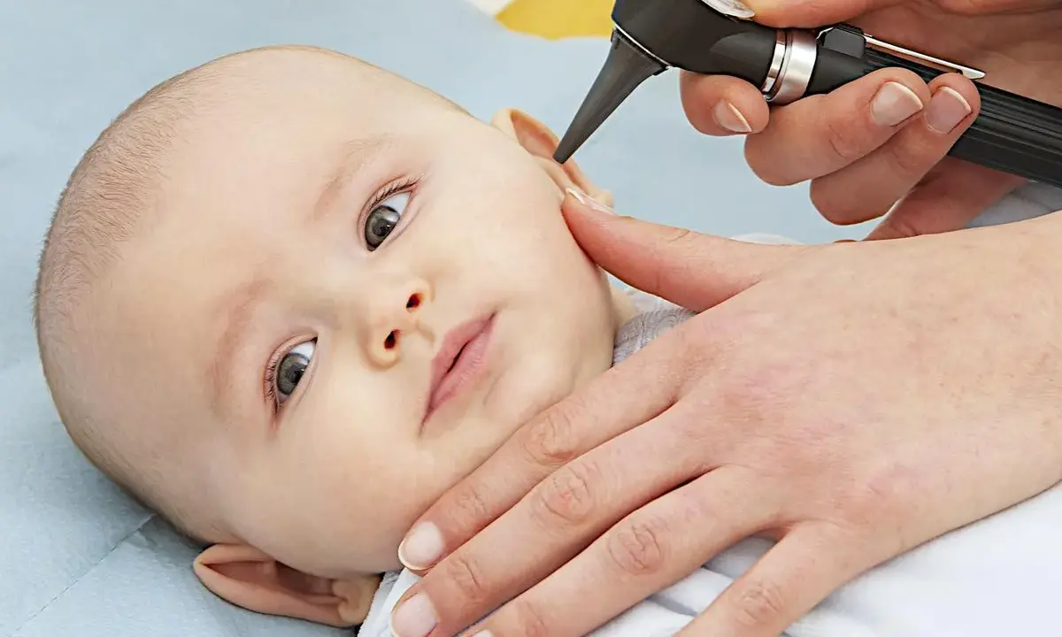 Esame dell'orecchio di un neonato per diagnosticare un'otite.