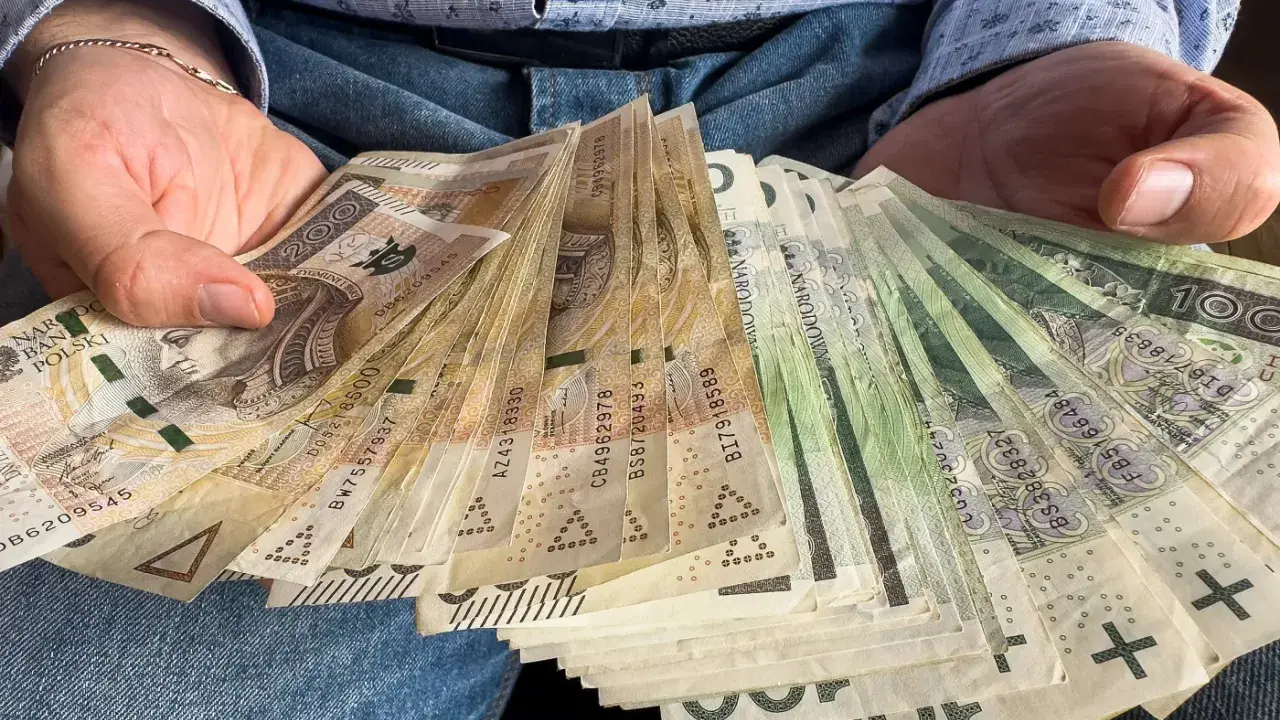 Ręce trzymające stos banknotów 100 zł i 200 zł. To darowizna od rodziców na nowy cel.