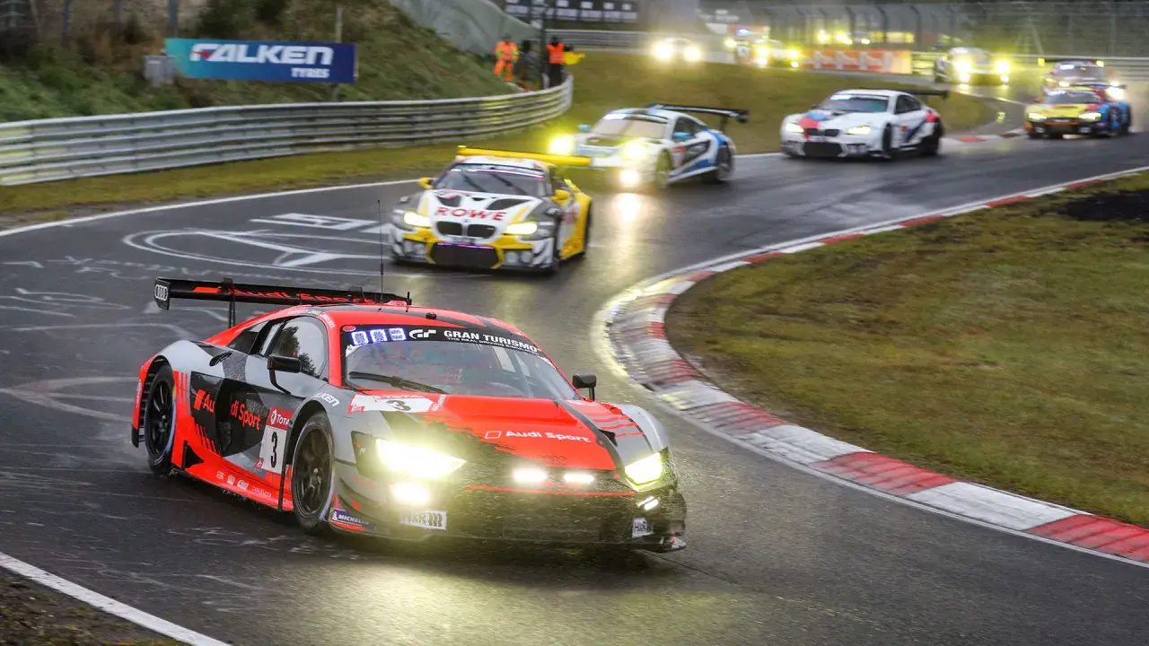 Un Audi R8 rojo y negro compite en las 24 Horas Nürburgring, con otros coches de carreras en la pista mojada.