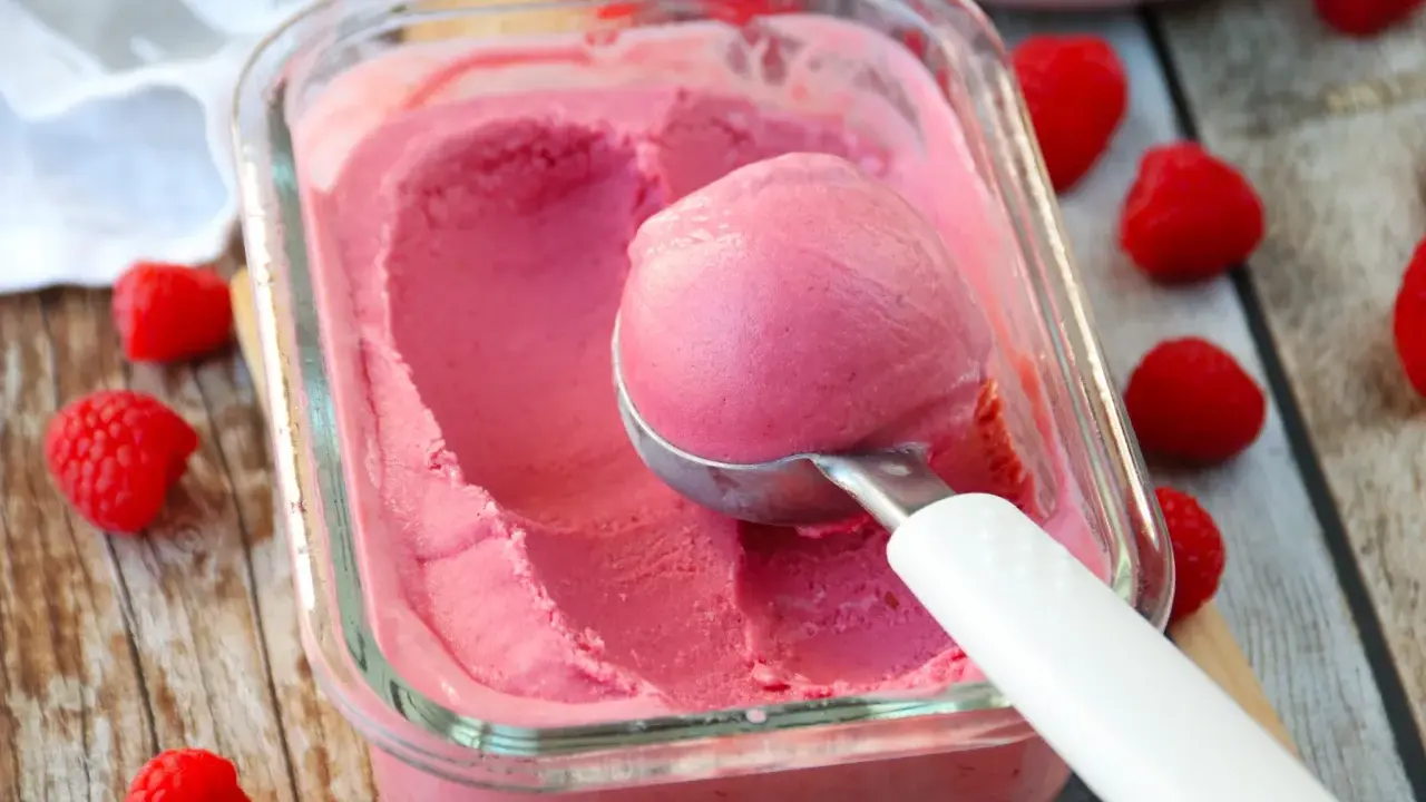 Glace framboise sans sorbetière, on dirait qu'elle est faite avec du lait concentré. Une boule est prélevée avec une cuillère.