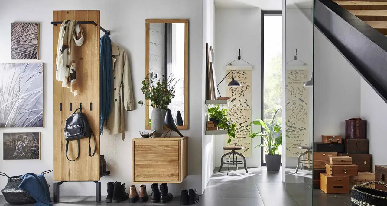 Une entrée chaleureuse avec un porte-manteau en bois, des tableaux, un miroir et des boîtes de rangement. Une belle idée déco pour une entrée de maison fonctionnelle et stylée.