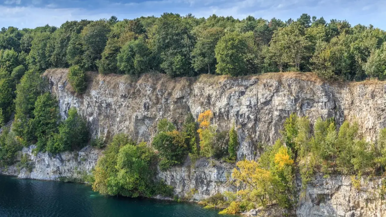 Skałki Twardowskiego w Krakowie, z malowniczym kamieniołomem i turkusową wodą, otoczone bujną zielenią drzew.