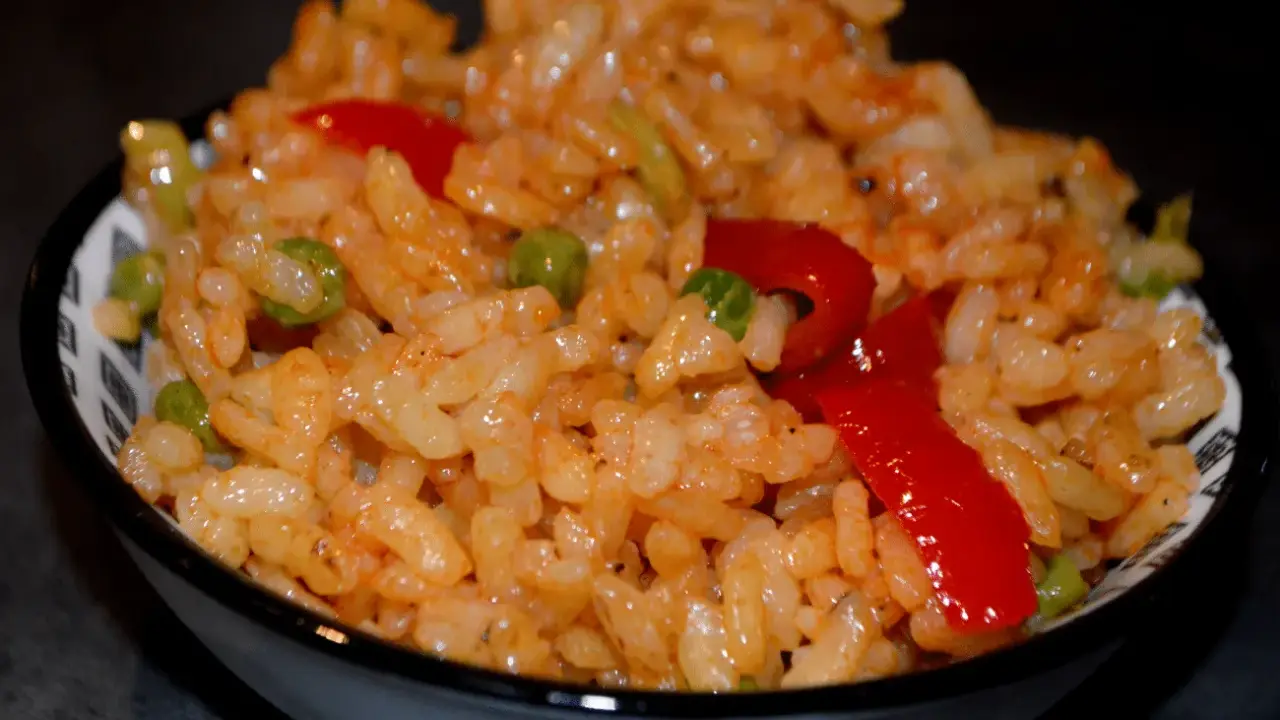 Un bol de riz coloré avec des petits pois et des poivrons rouges, parfait pour une recette salade riz facile et rapide.