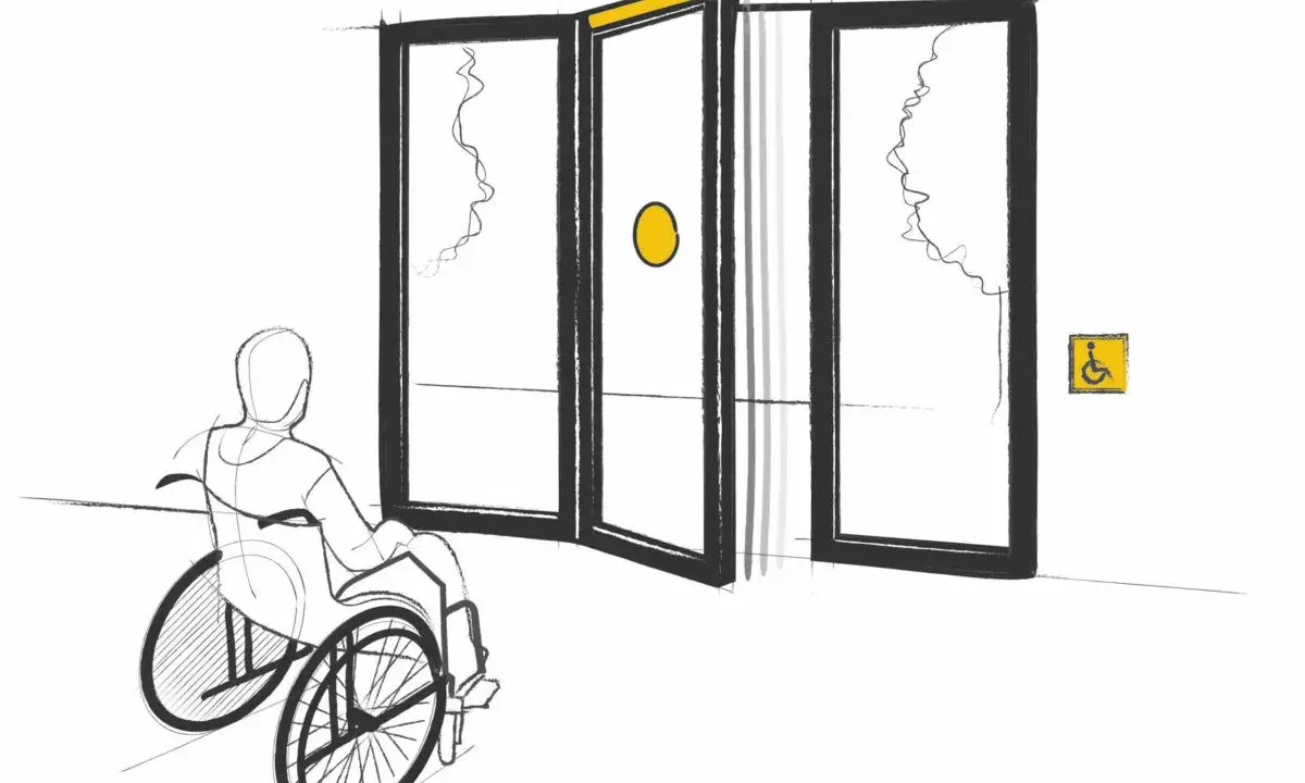 Persona en silla de ruedas se acerca a puertas automáticas, cumpliendo la normativa de puertas de portales para accesibilidad.
