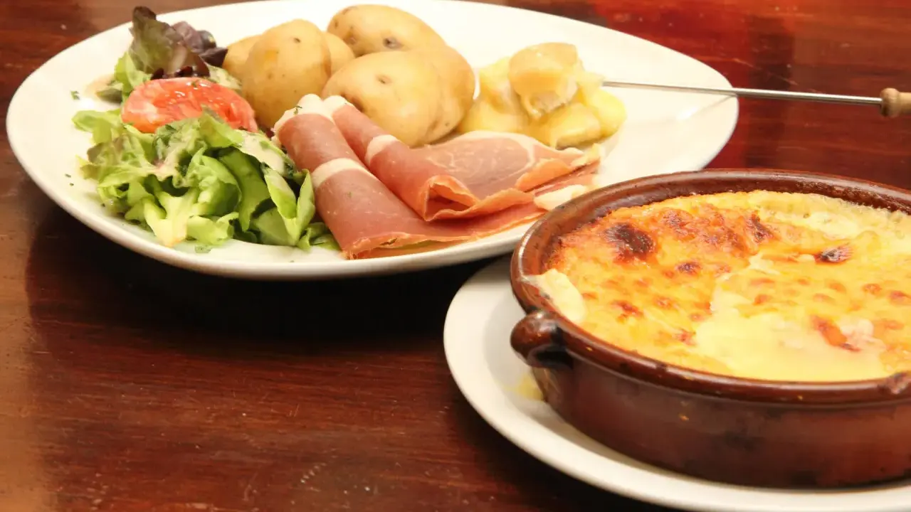 Un plat de spécialité auvergnate : pommes de terre, jambon cru, salade et un gratin de fromage fondant.