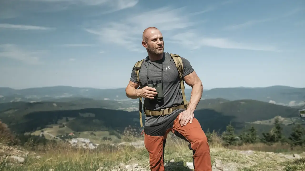Mężczyzna w letnim stroju górskim: koszulka, spodnie trekkingowe i plecak. Idealny przykład, jak się ubrać w góry latem.