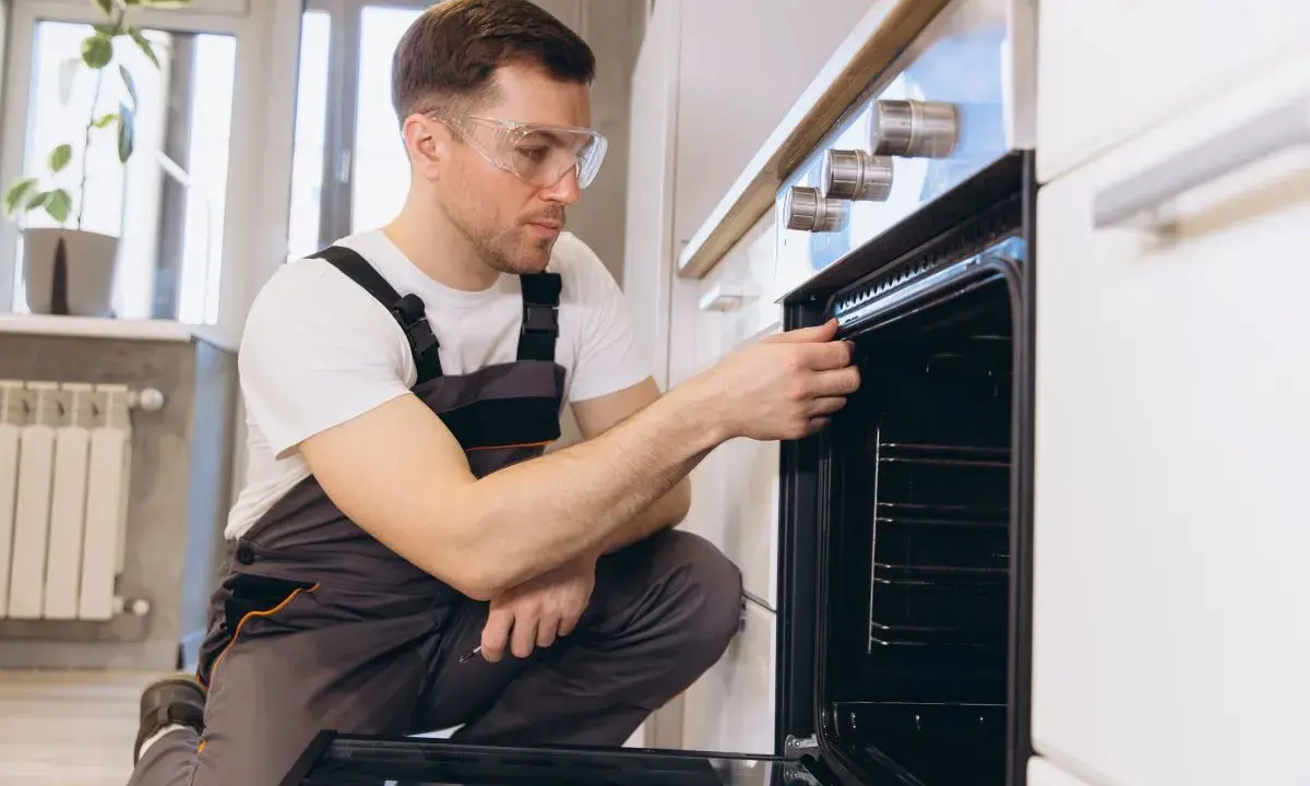 Un technicien vérifie la hauteur et l'étanchéité d'un four encastrable.